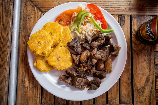 Crispy fried pork chunks served with tostones, the classic way to plate masitas de puerco